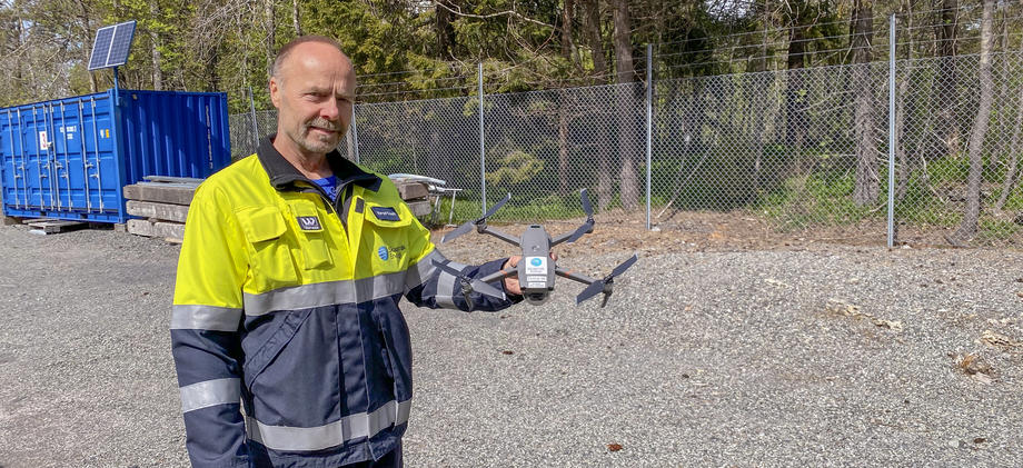 Mann i arbeidsklær viser frem drone.